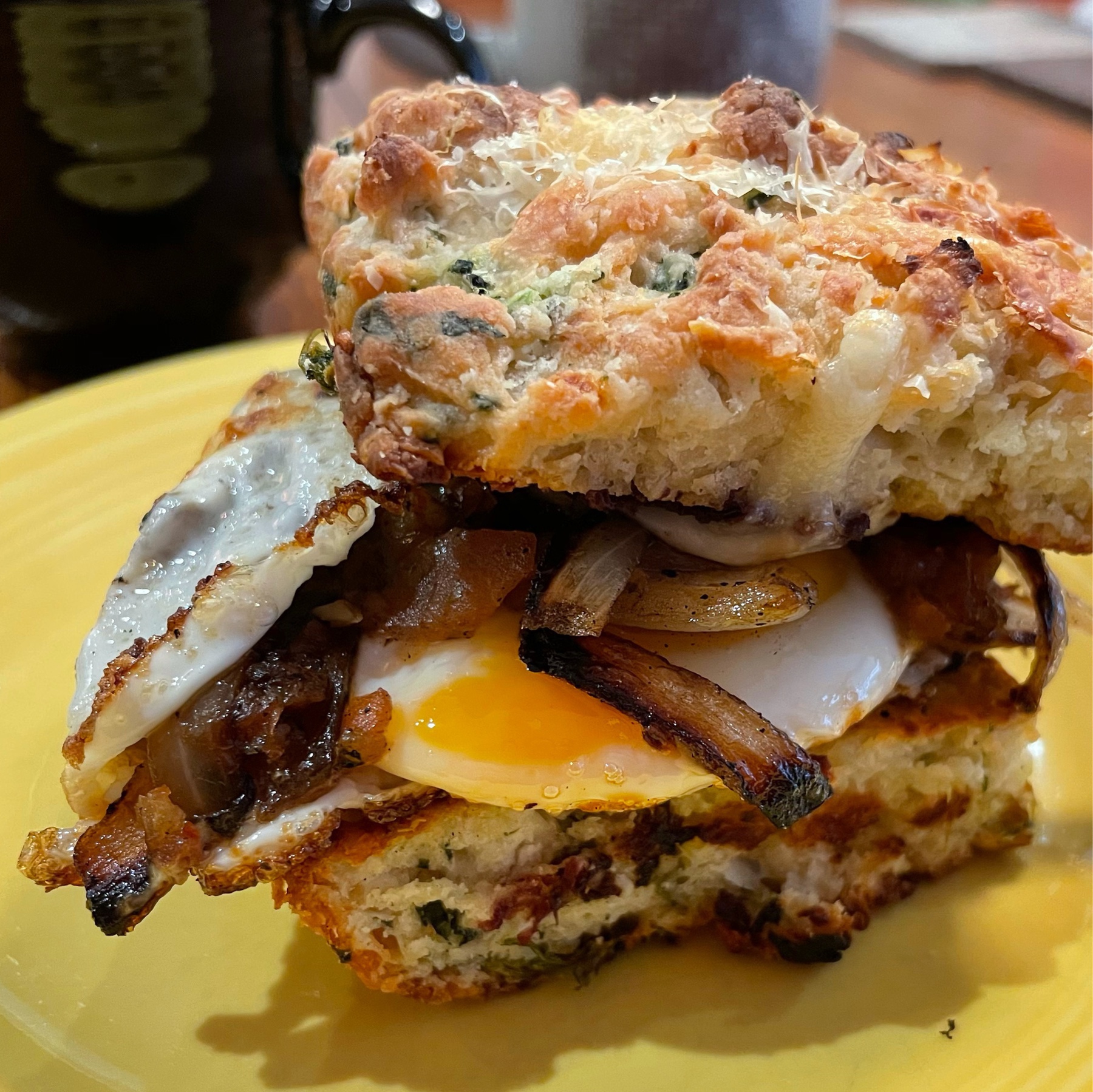 A messy breakfast sandwich on a yelliw plate.
